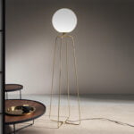 Floor lamp with base made of golden steel and white tinted glass bulb.